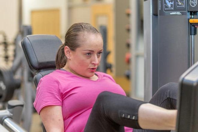 一名妇女坐在腿上，正在使用腿部按压锻炼机